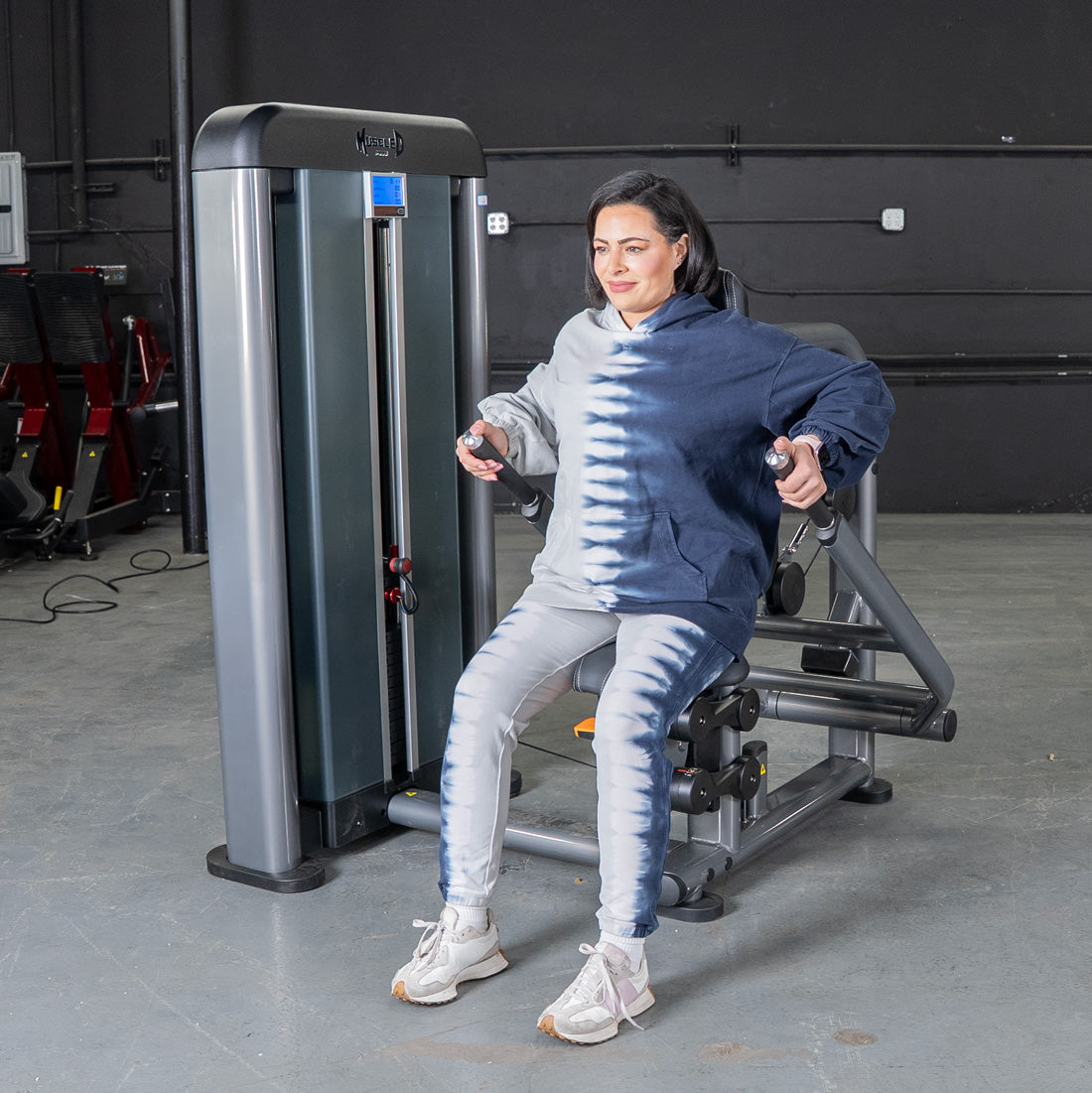 Woman using Elite Plus Triceps Press machine at the gym.