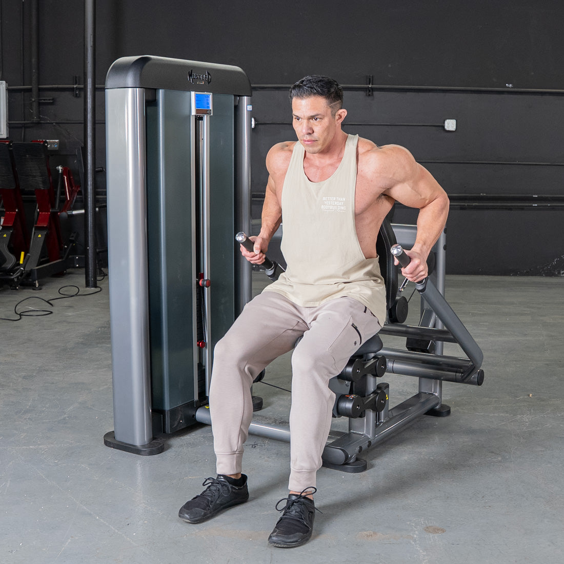 Muscular man using a triceps press machine at the gym.