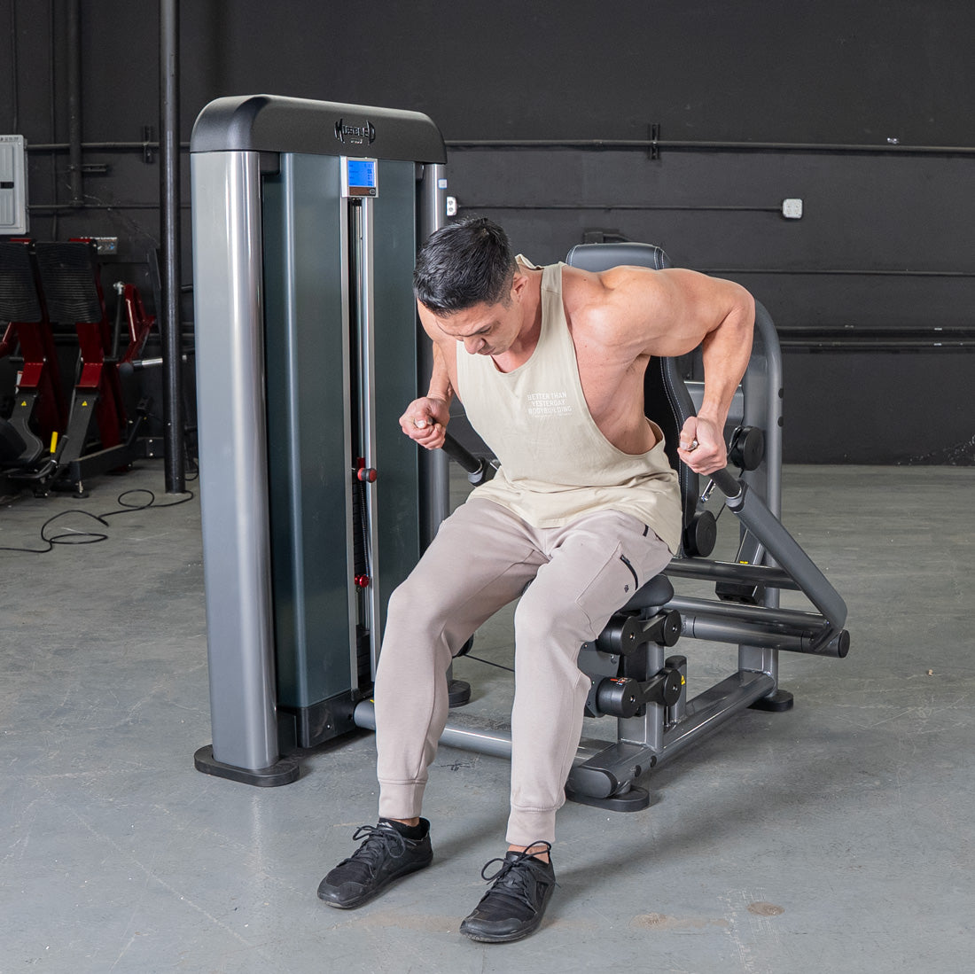 Man performing triceps press on Elite Plus machine in gym.