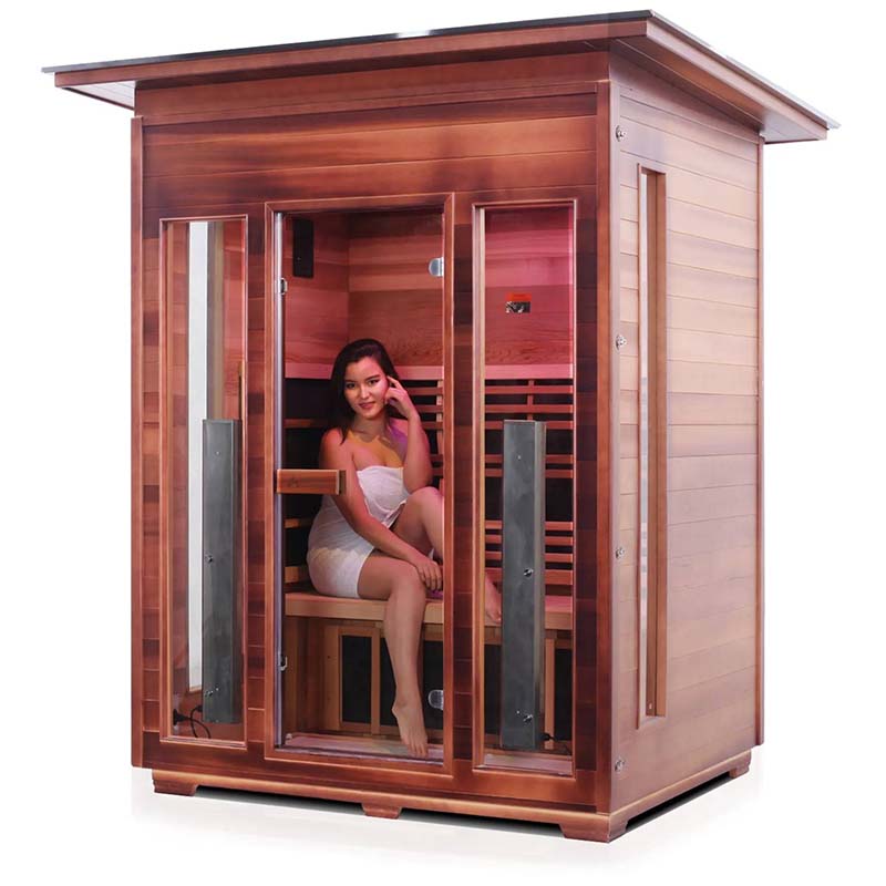 Woman sitting inside a wooden home sauna with glass door