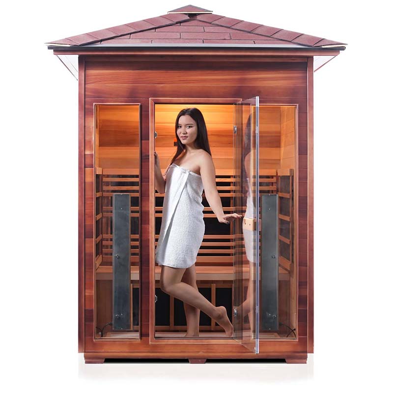 Woman in white towel inside a cedar infrared sauna with glass door.