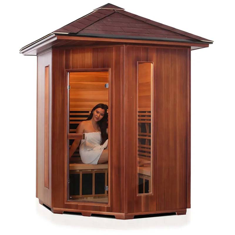 Woman relaxing in a wooden infrared sauna with glass door and modern design.