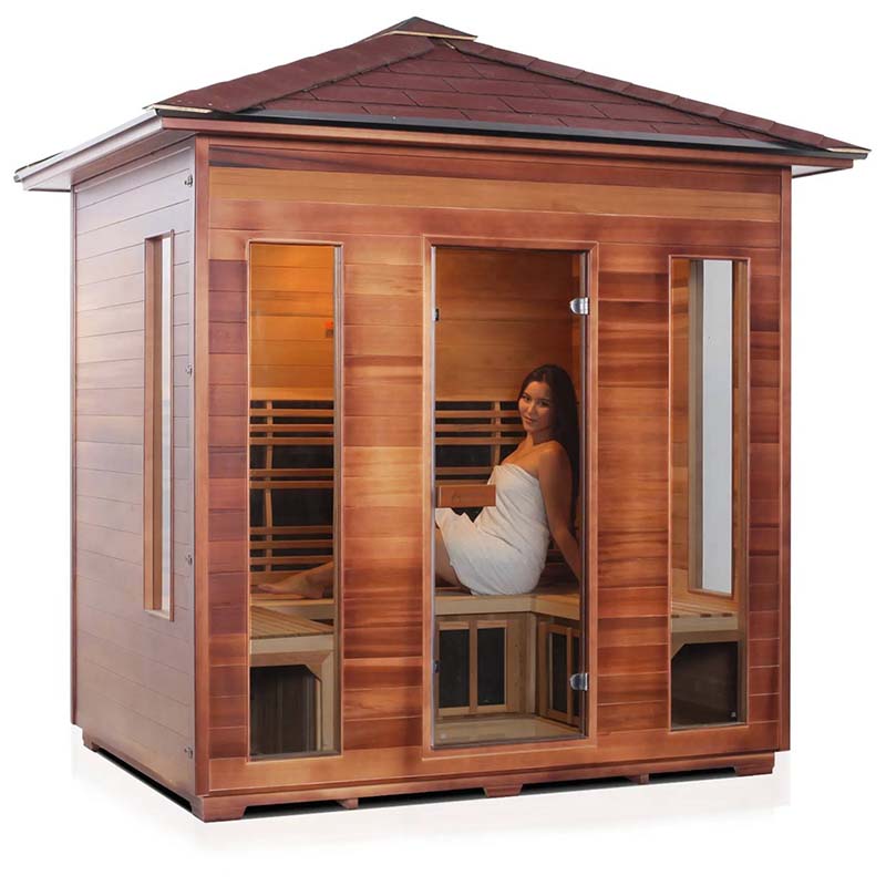 Outdoor cedar sauna with a woman relaxing inside, featuring glass door and windows.