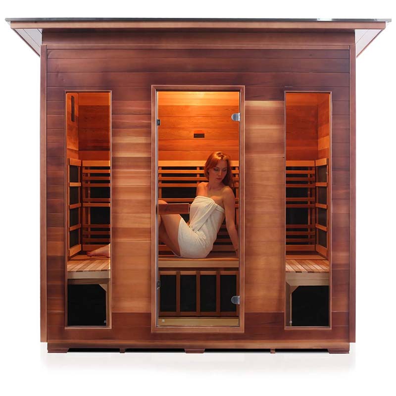 Woman relaxing in a wooden infrared sauna cabin, wrapped in a towel.