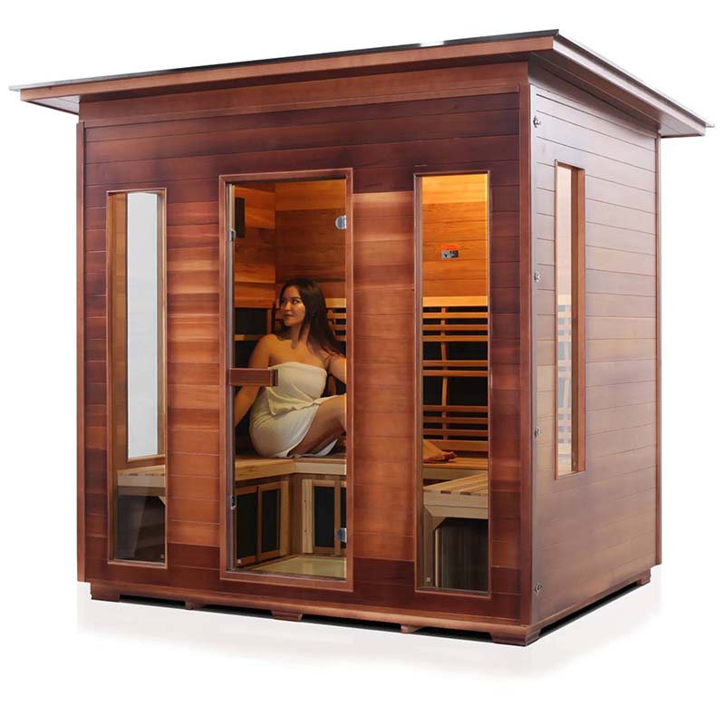 Cedar infrared sauna with glass doors and a woman relaxing inside.