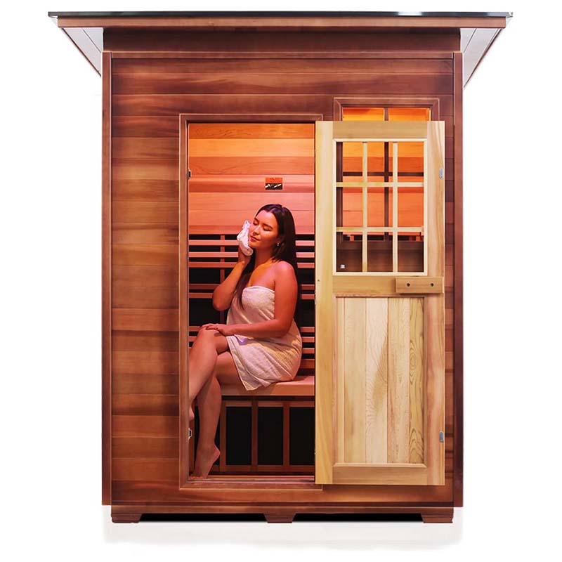 Woman relaxing in a wooden infrared sauna, wrapped in a towel, enjoying the warmth.