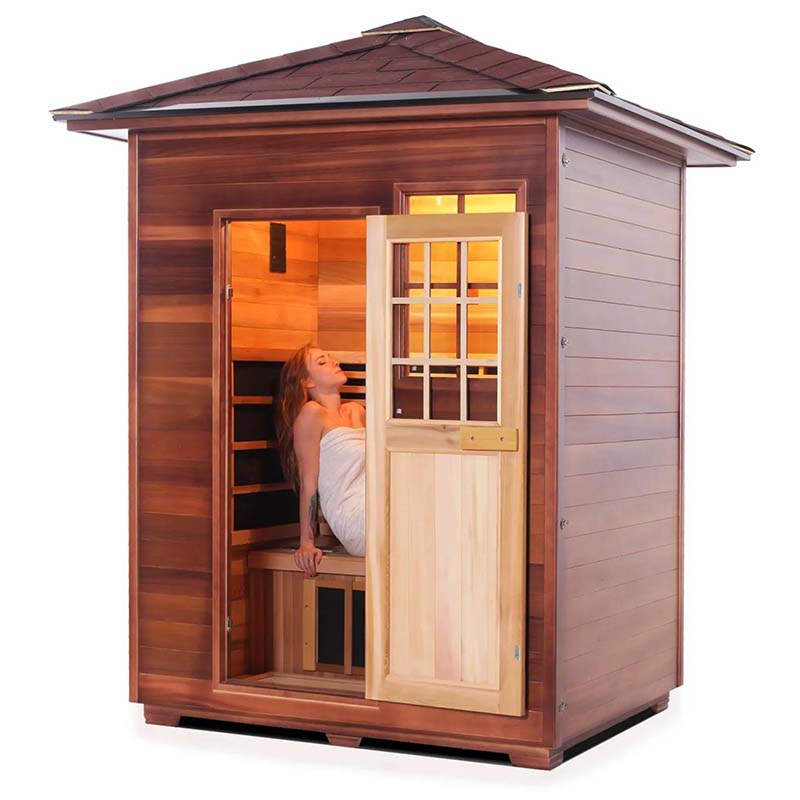 Outdoor cedar infrared sauna with a woman relaxing inside.