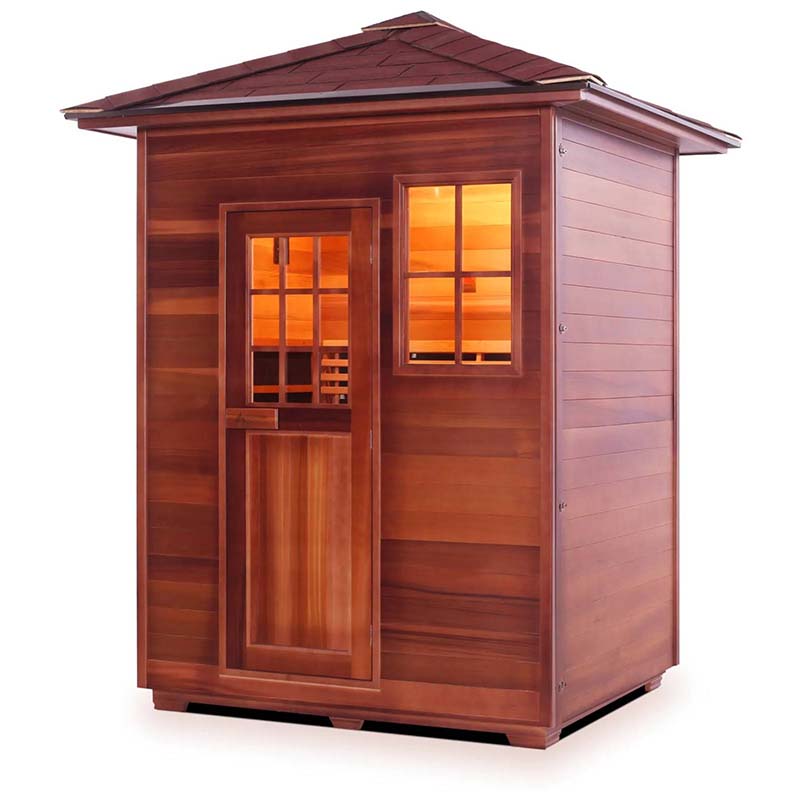 Outdoor cedar sauna with warm interior lighting and a shingled roof.
