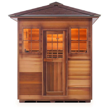 Outdoor cedar sauna with a shingled roof, featuring warm interior lighting.