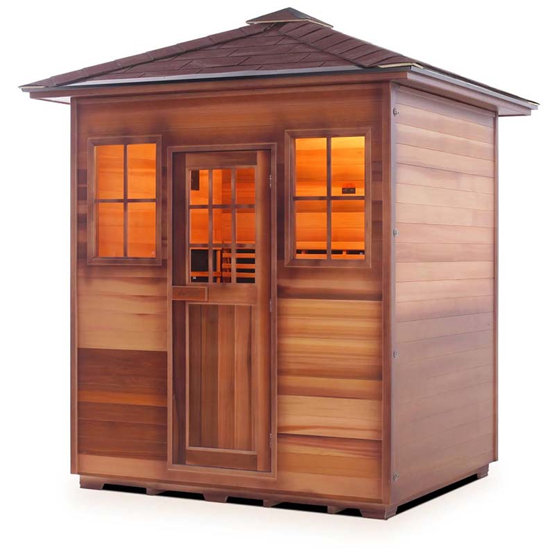 Outdoor cedar sauna with warm interior lighting and shingled roof.