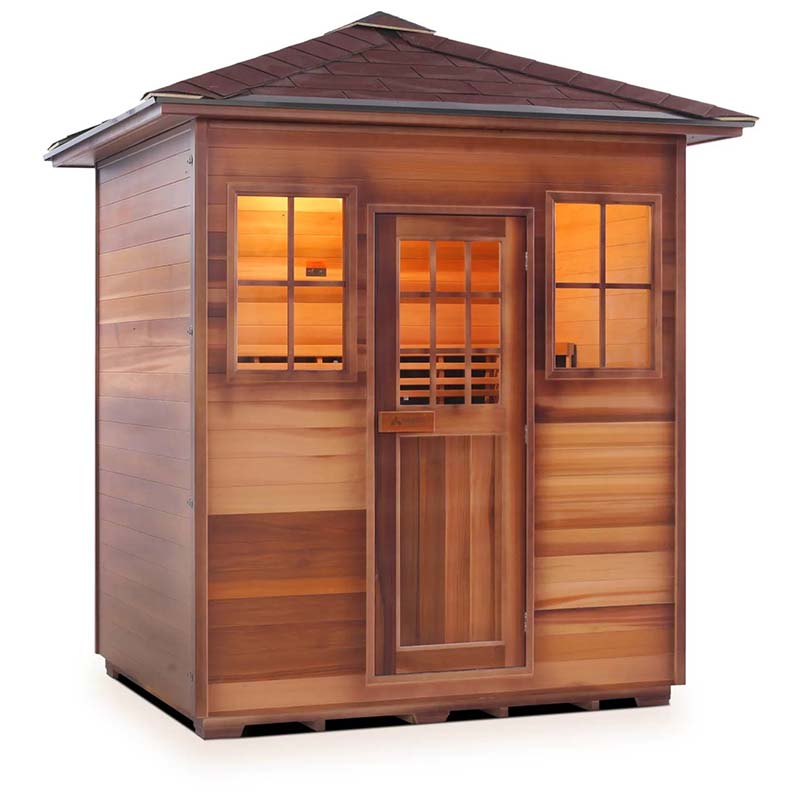 Outdoor cedar sauna with shingled roof and illuminated windows for home relaxation.