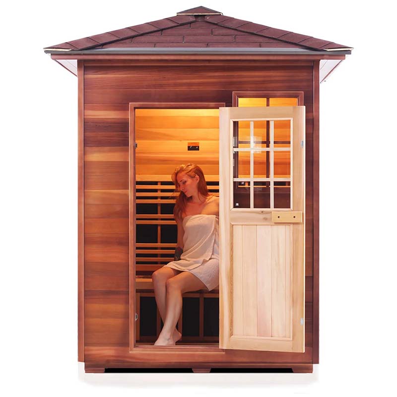 Woman relaxing in a cedar infrared sauna with open door.