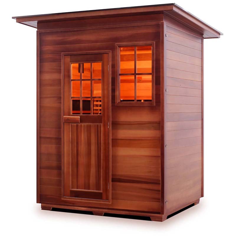 Outdoor cedar sauna with glass door and window, featuring warm interior lighting.