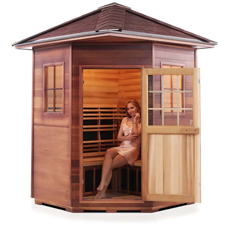 Outdoor cedar sauna with a woman seated inside, showcasing its spacious design and warm lighting.
