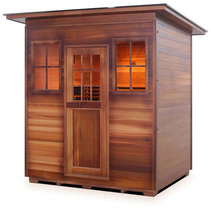 Outdoor cedar sauna cabin with glass windows and warm interior lighting.