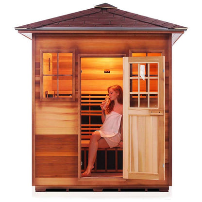 Woman relaxing in a wooden infrared sauna drinking water.
