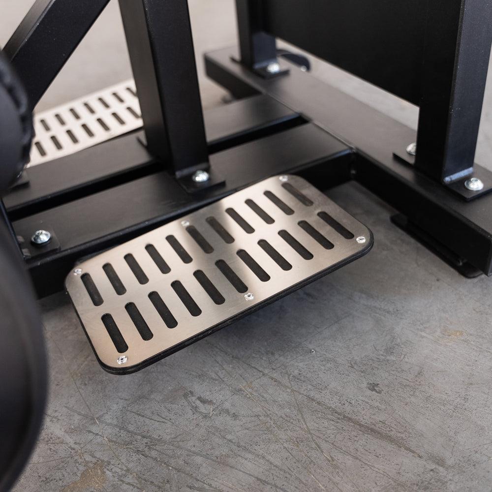 Industrial metal foot pedal with slotted grip plate on gym machine.