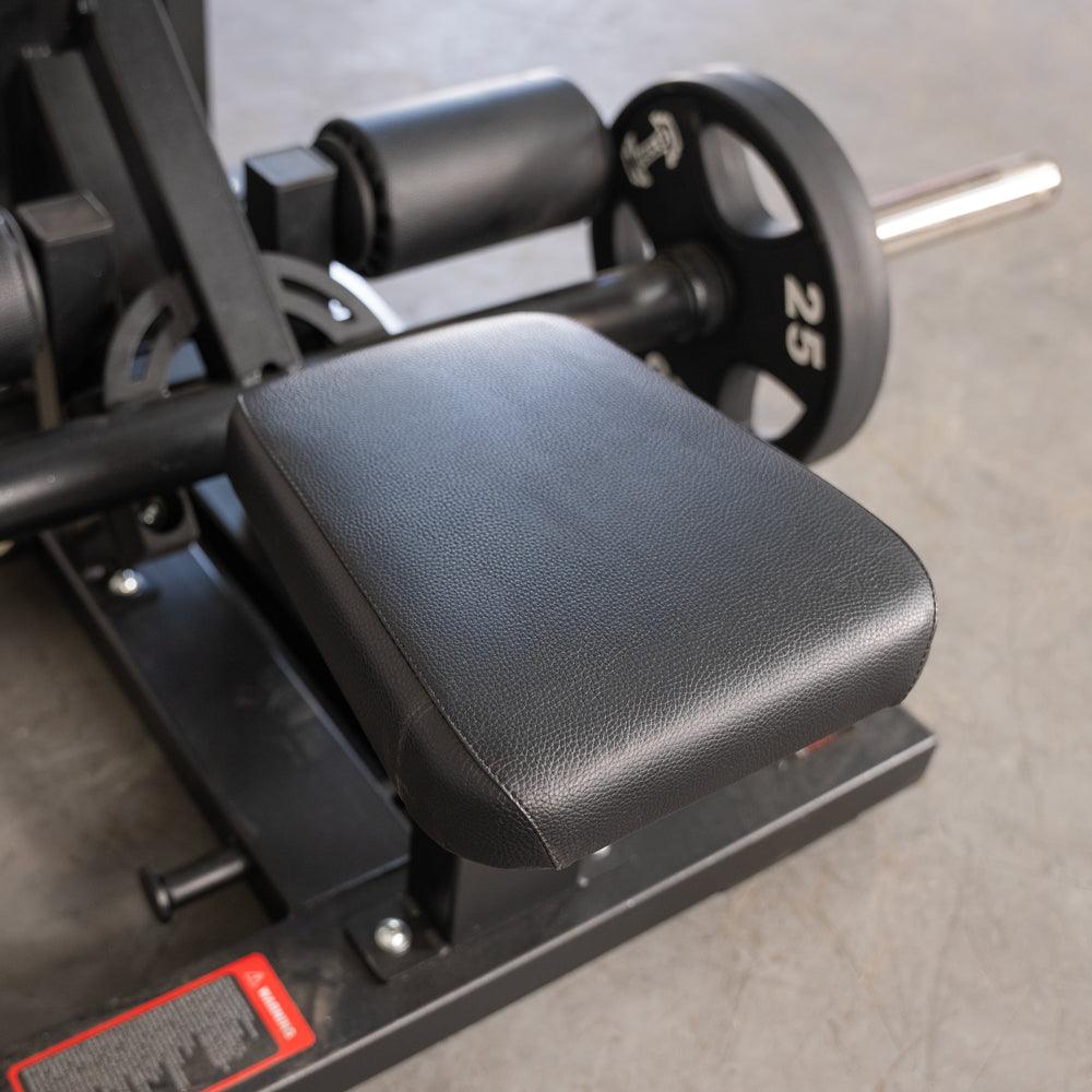Black padded seat on weight-training machine with a 25 lb plate in the background.