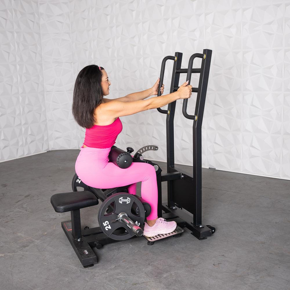 Woman in pink workout gear using a back extension machine at the gym.
