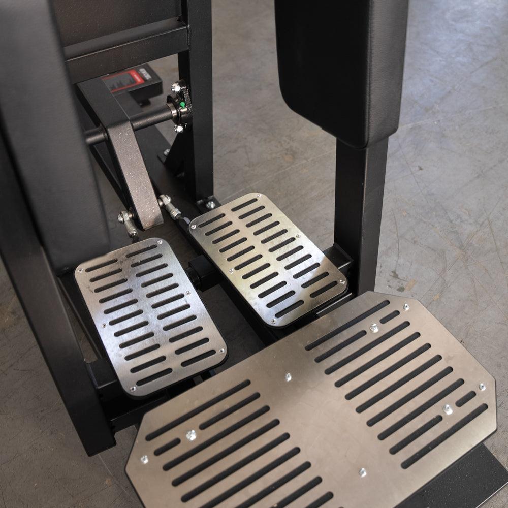 Hip thrust machine with metal slotted foot pedals and platform.