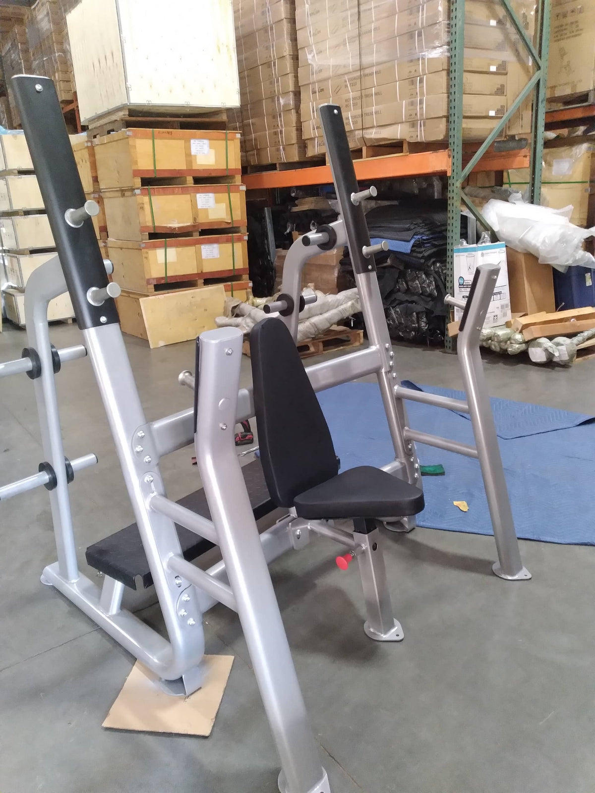 Weight machine with black padded seat in a warehouse setting.