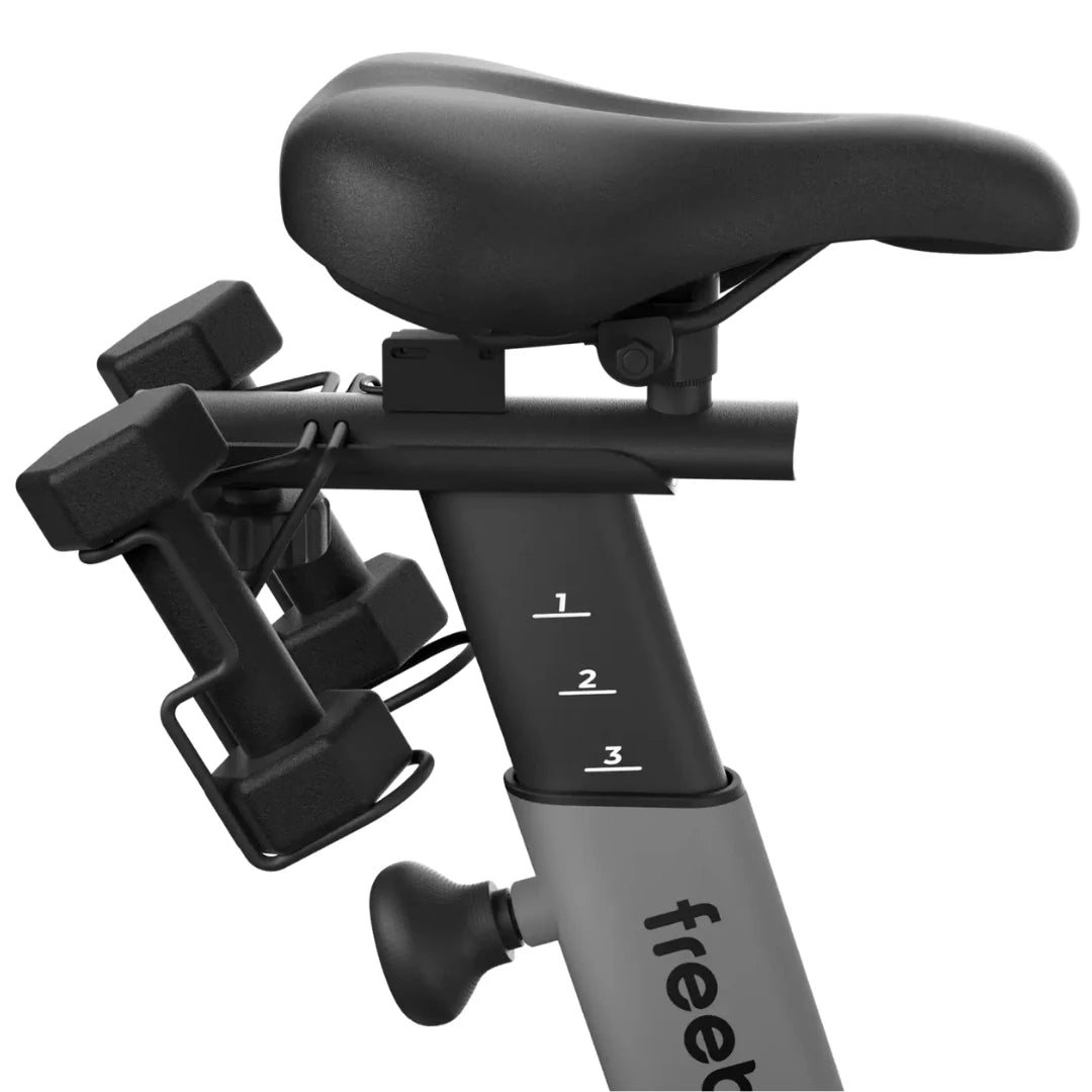 Close-up of the Freebeat Boom Stationary Exercise Bike, featuring a black seat, adjustable handlebars, and attached weights.