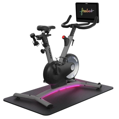 Freebeat Boom Stationary Exercise Bike with a digital display and adjustable handlebars, featuring a sleek design and illuminated base on a black mat.
