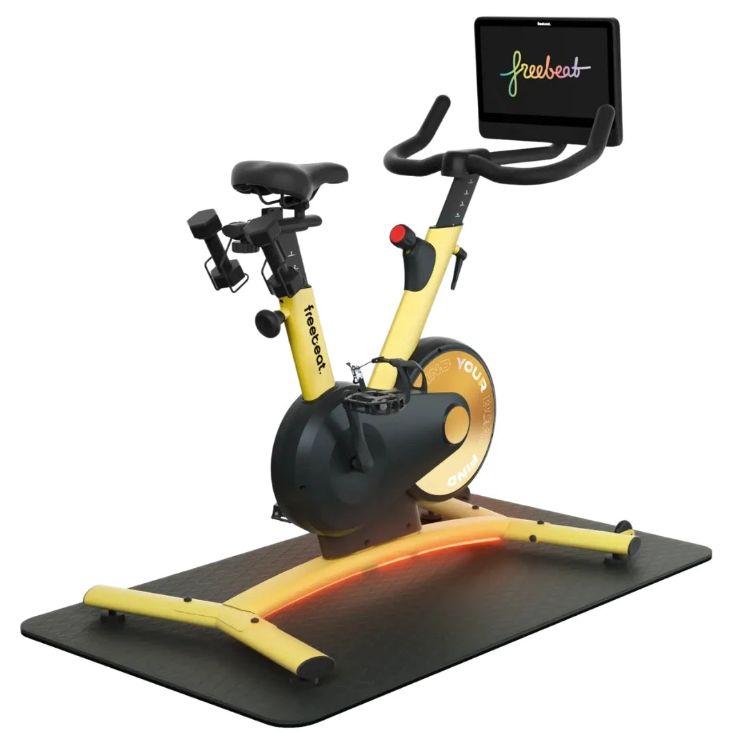 Freebeat Boom Stationary Exercise Bike featuring a sleek design with a yellow frame, adjustable handlebars, and a digital display. The bike is positioned on a textured mat.