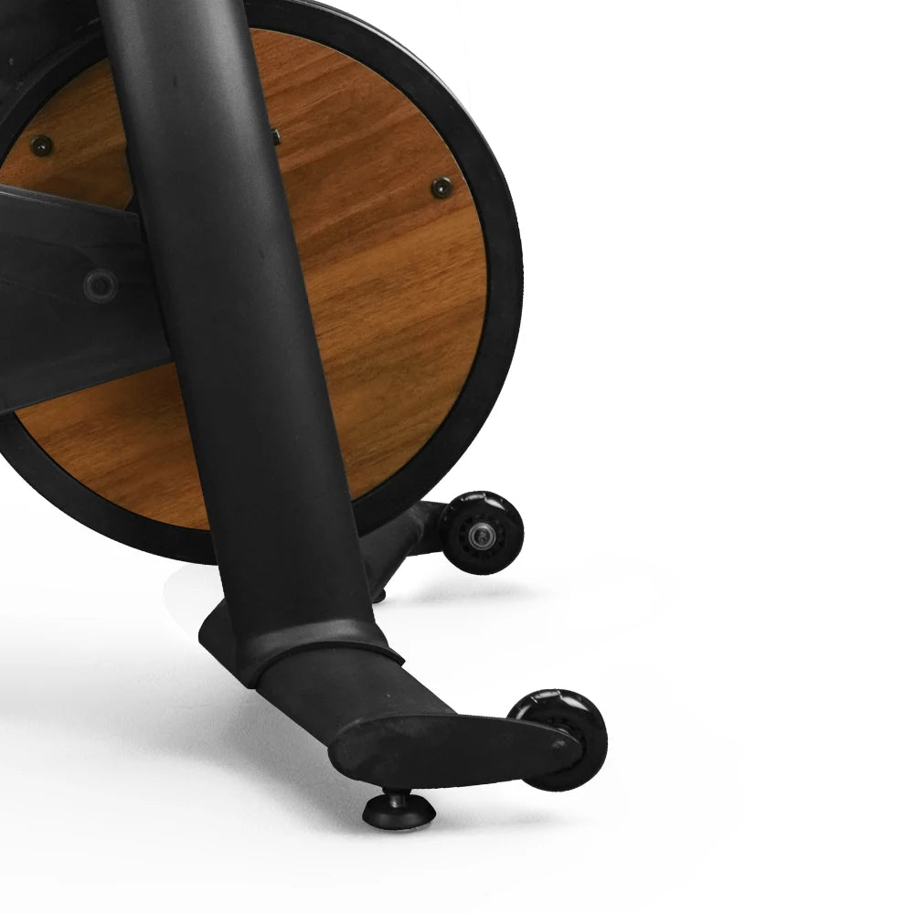 Stationary bike with wooden flywheel and black frame, featuring front-mounted wheels for easy movement.