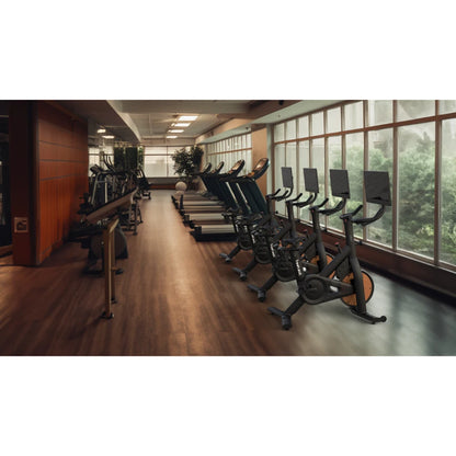 Modern gym with treadmills and stationary bikes lined up on wooden flooring.