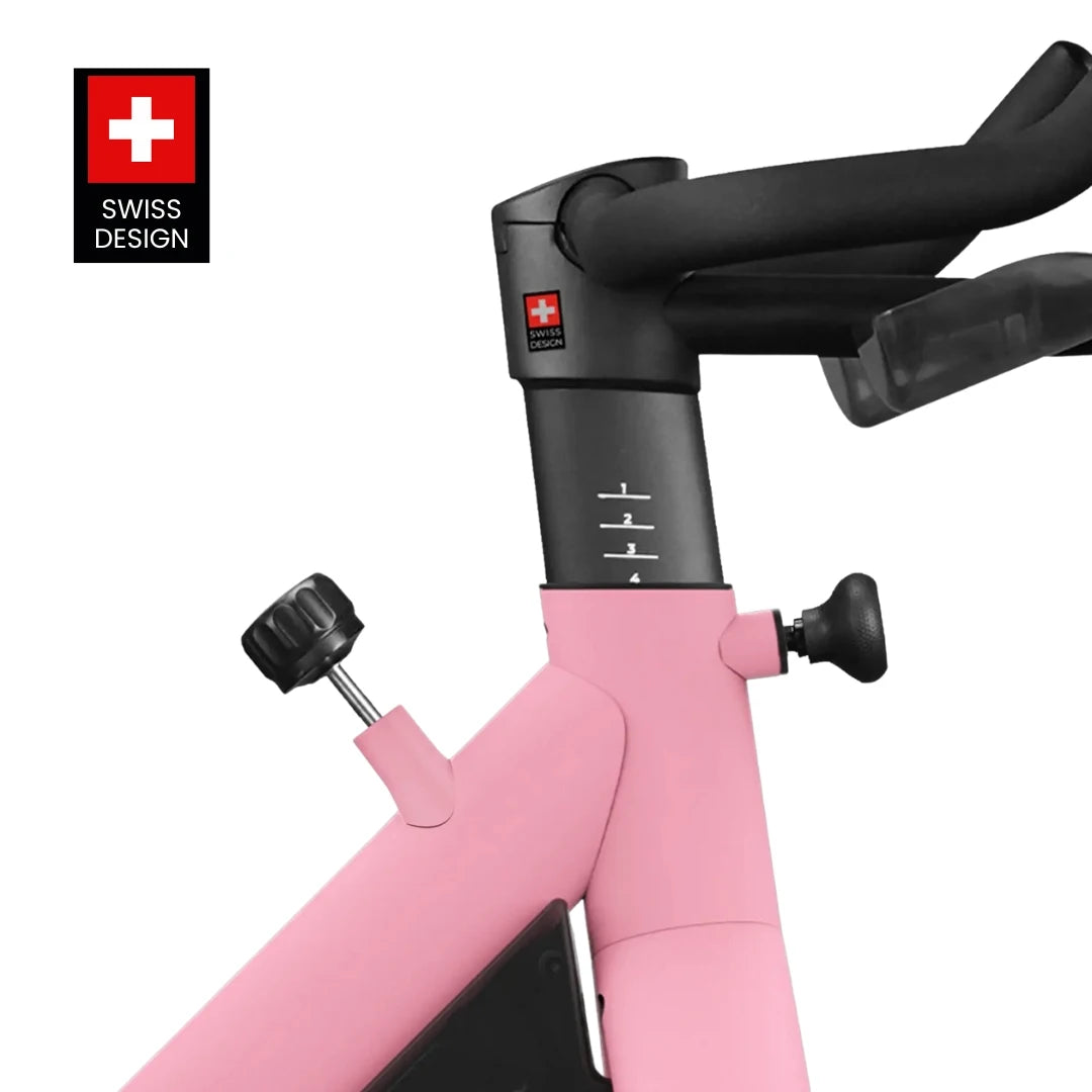 Close-up view of the Freebeat Lit Stationary Exercise Bike featuring a pink frame, adjustable components, and a Swiss design logo.