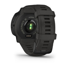 Back view of a Garmin Instinct 2 smartwatch in dark green, showcasing the heart rate sensor and charging contacts.