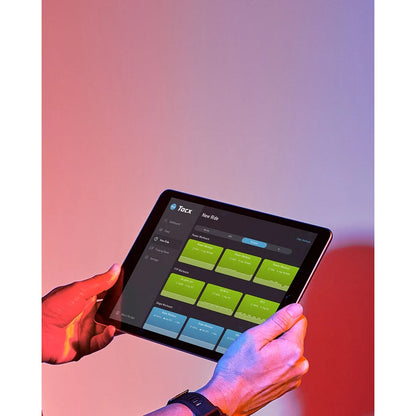 Person using Tacx cycling app on tablet against vibrant background.