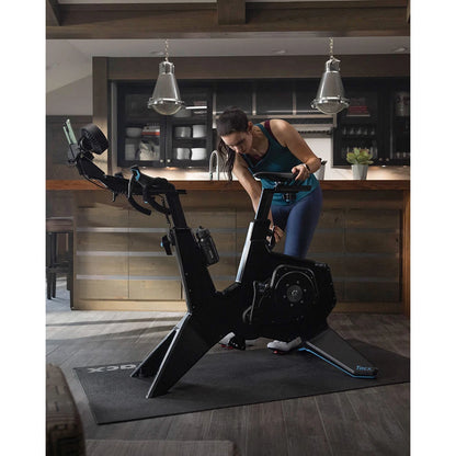 Woman using Tacx NEO Bike Smart trainer in a modern kitchen.