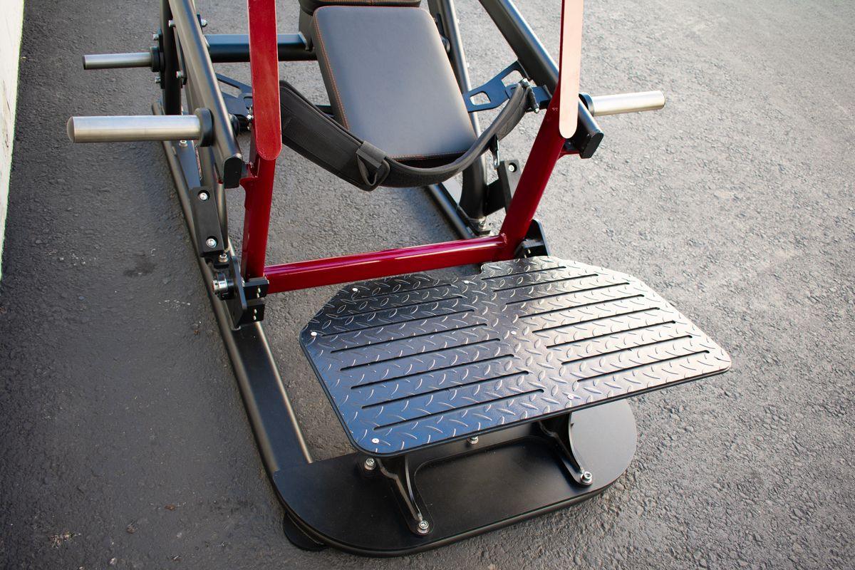 Fitness machine foot platform with red frame and diamond-plate surface.