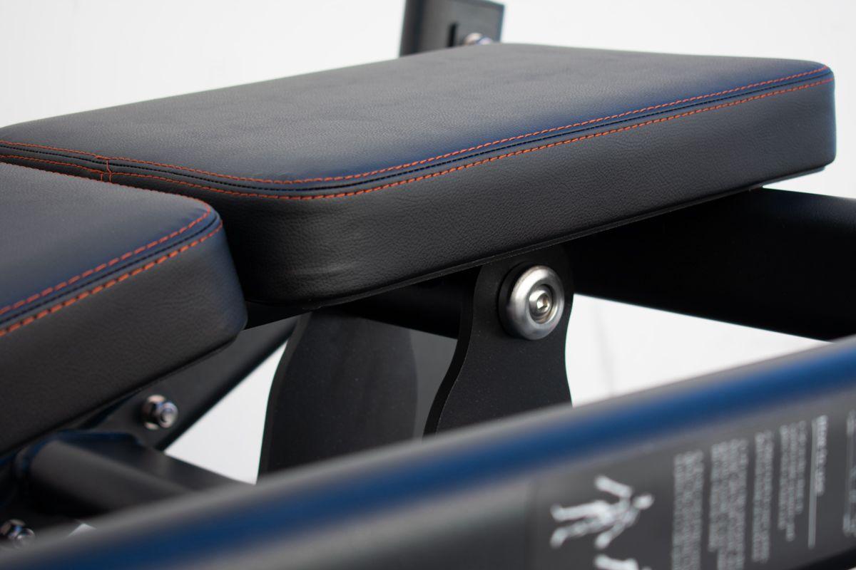 Close-up of blue padded bench seat with orange stitching and metal bolt.