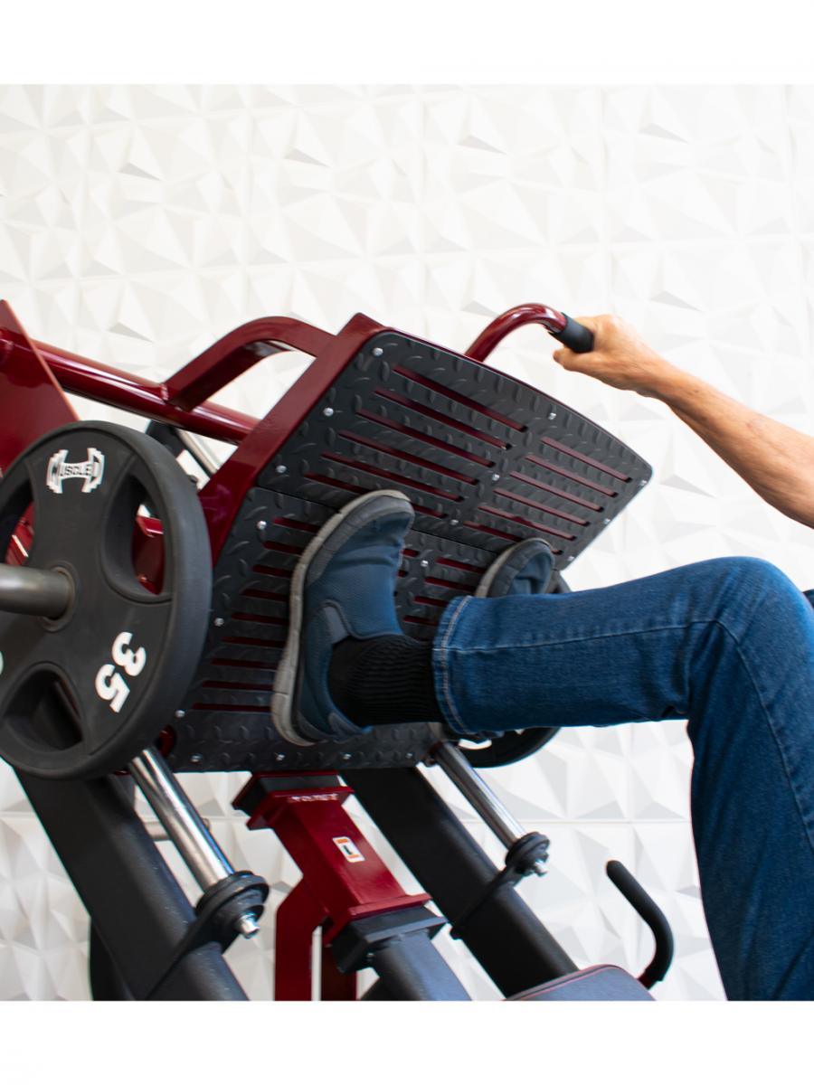 Person using a leg press machine, pushing pedals with foot.