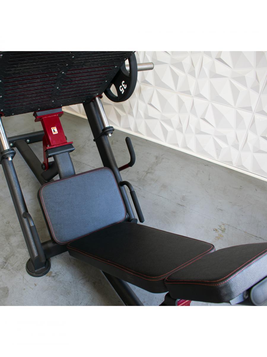 Leg press machine with padded seat and backrest in gym.