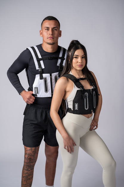Athletic couple wearing black and white weighted vests posing in studio.