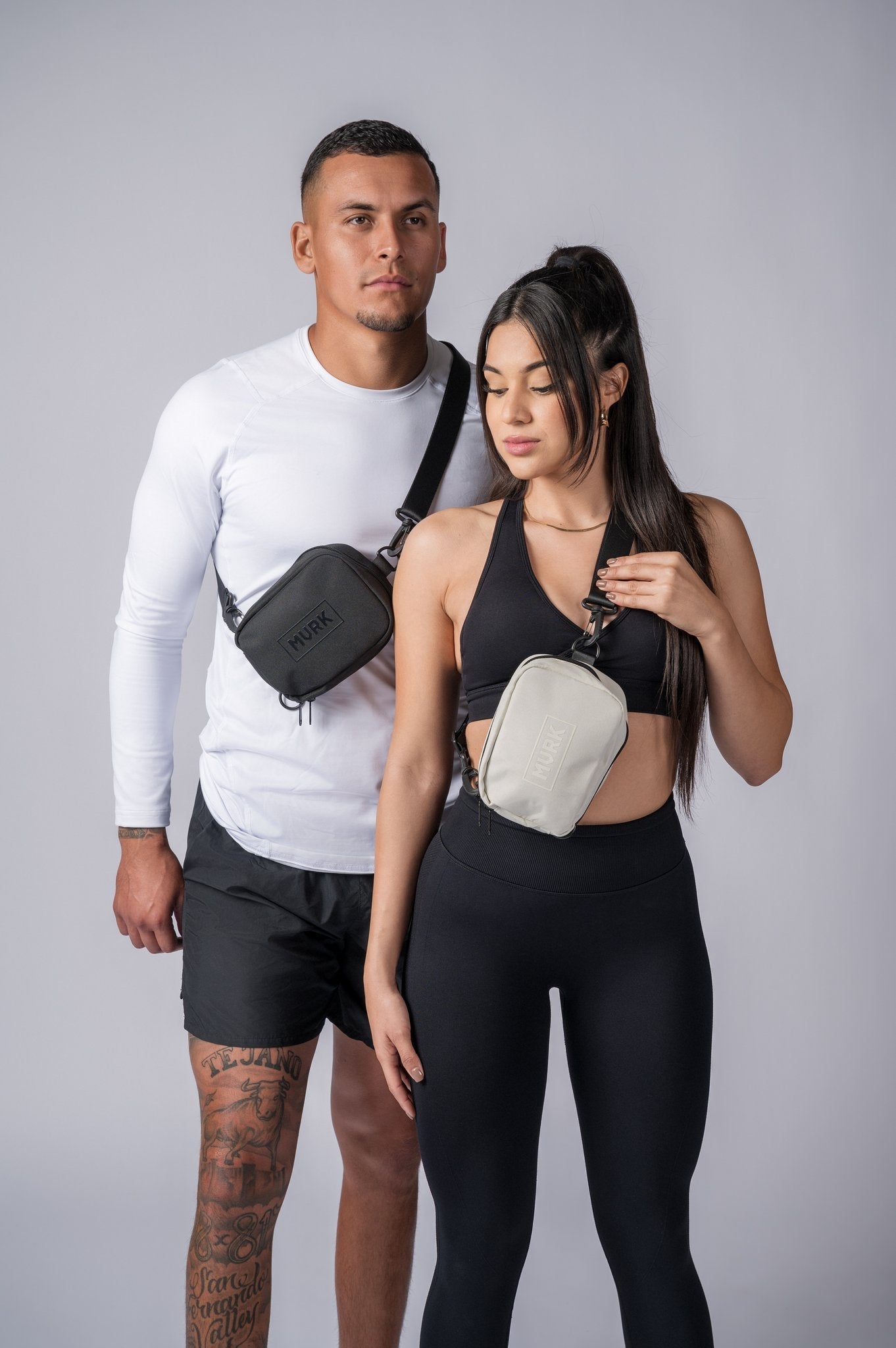 Athletic couple posing with small crossbody pouches labeled MVRK.