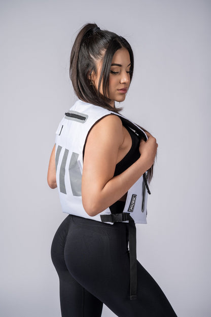 Athletic woman in white vest and black leggings, side profile pose.
