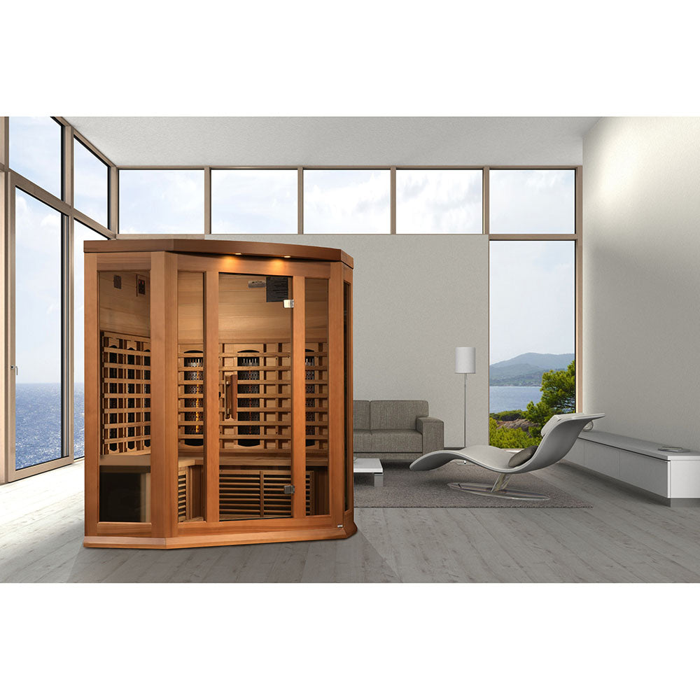 Maxxus 3 Person Full Spectrum Infrared Corner Sauna displayed in a modern living room with large windows and a view of the ocean.