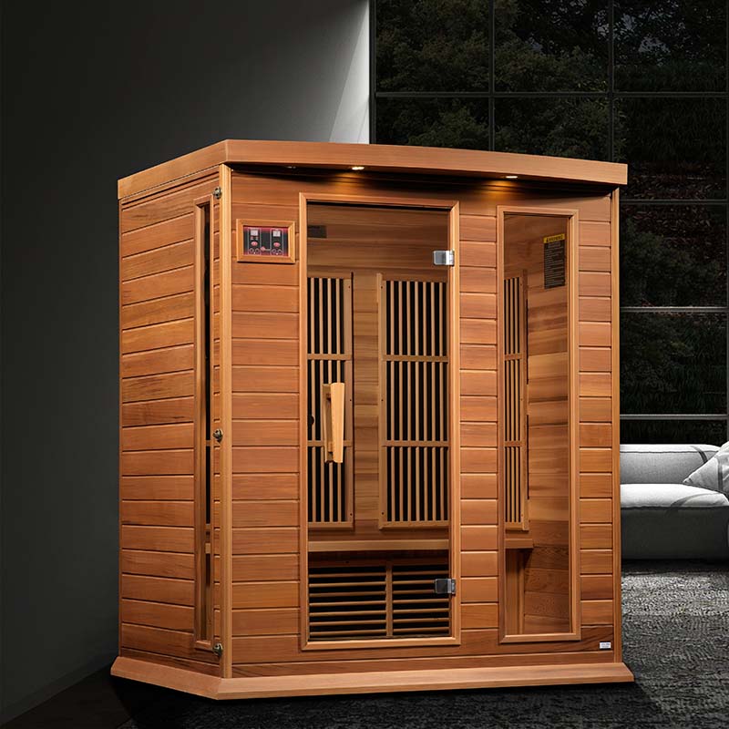 Maxxus MX-K306-01 Far Infrared Sauna, a wooden sauna with a front door and slatted panels, set in a modern interior with a sofa in the background.