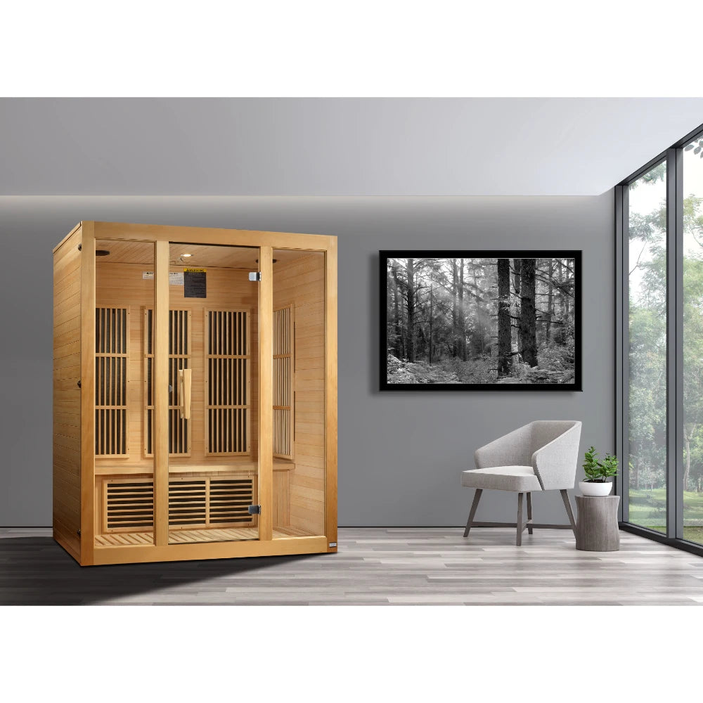 Maxxus Bellevue 3 Person Far Infrared Sauna displayed in a modern room with a gray wall, a framed black and white photograph, and a light-colored chair.