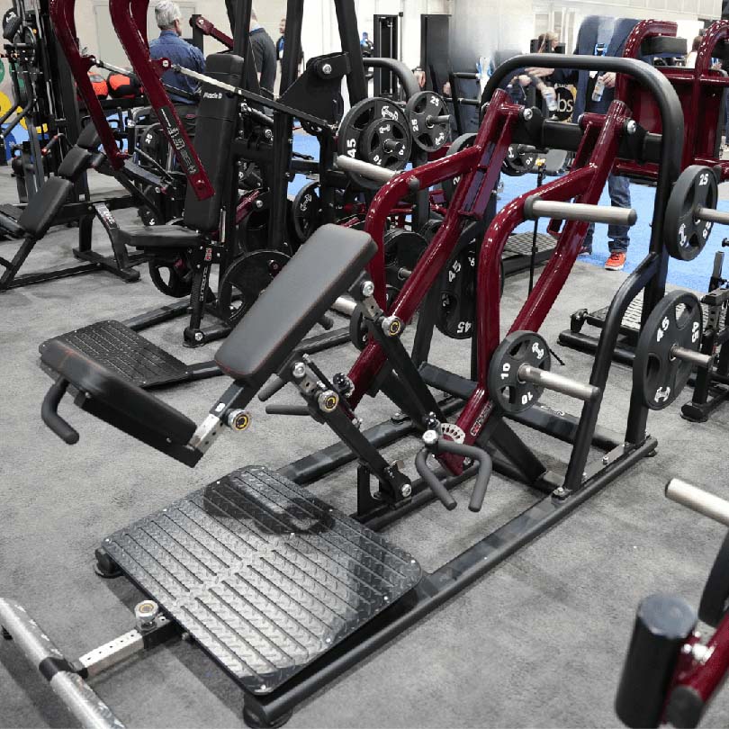 Leg press machine with red frame and adjustable seat for gym workouts.