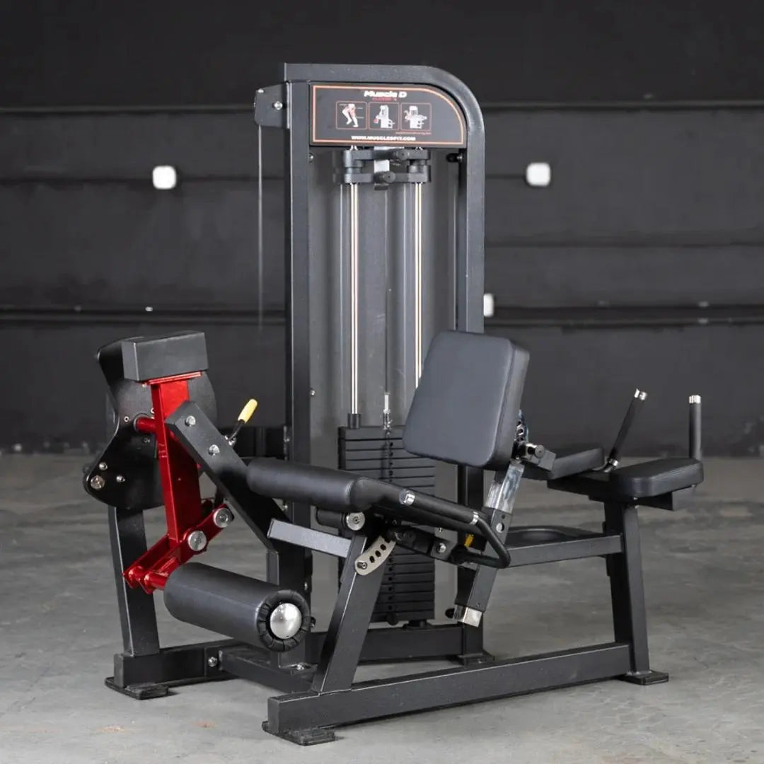 Black and red commercial leg extension and lying leg curl combo machine with dual padded seats and adjustable foot platforms, positioned in a gym setting against a dark wall.