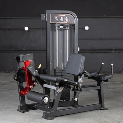 Black and red commercial leg extension and lying leg curl combo machine with dual padded seats and adjustable foot platforms, positioned in a gym setting against a dark wall.