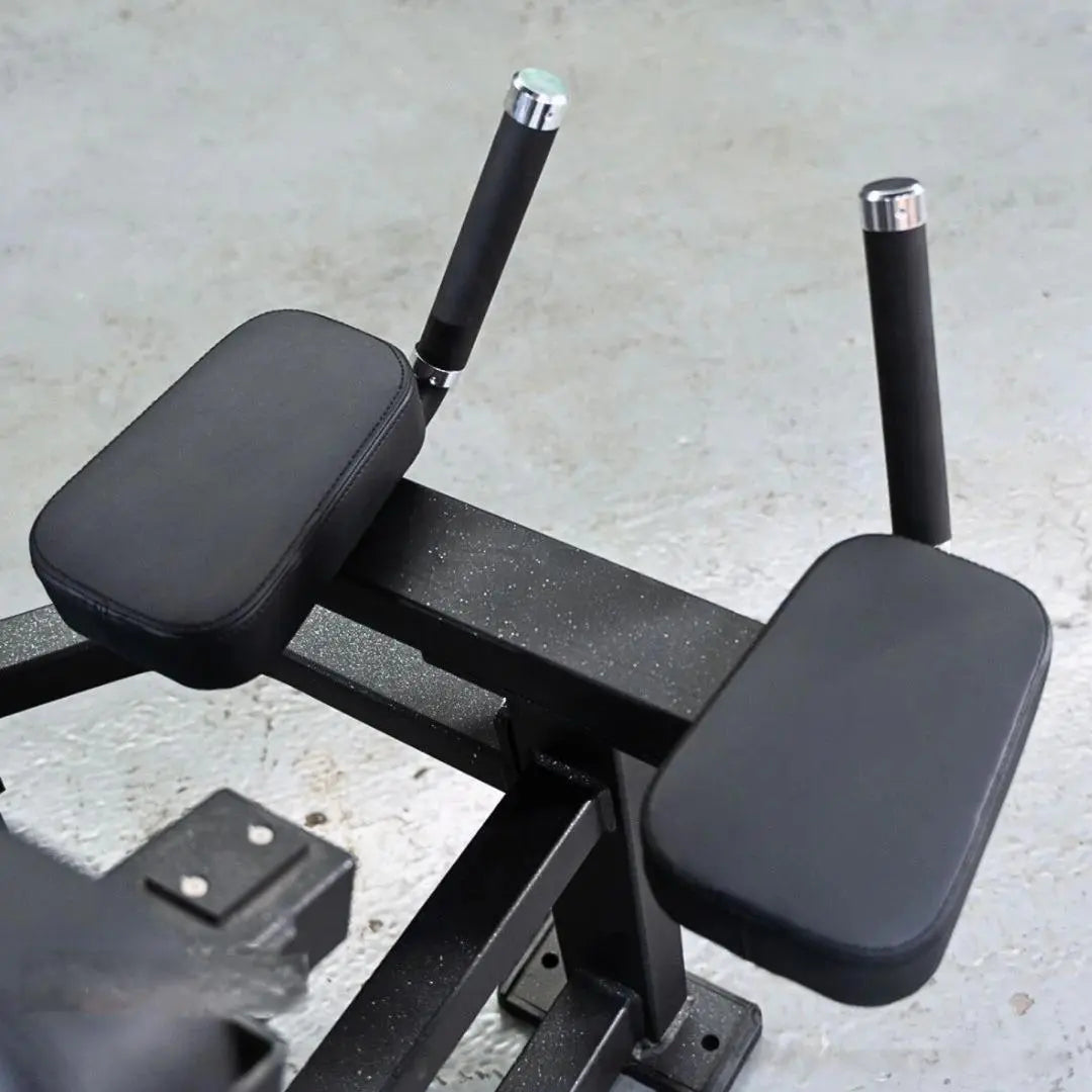 Black leg extension and lying leg curl combo machine with padded black seat and leg pads, chrome-accented handles, and textured black metal frame on concrete background.