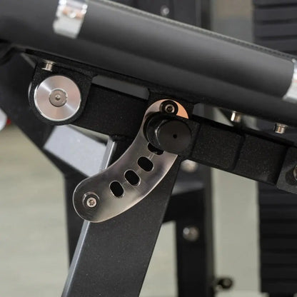 Close-up of a leg extension and lying leg curl machine showing the metal footplate with oval cutouts, silver adjustment dial, and black frame structure.