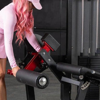 Woman performing a leg curl on a black and red leg extension/curl combo machine with padded foot rollers in a gym setting.